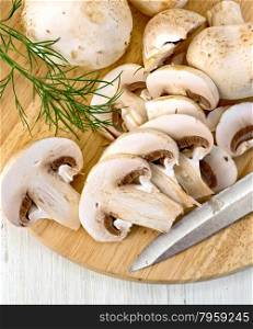 Champignons raw whole and sliced with a knife and a sprig of parsley on a wooden board