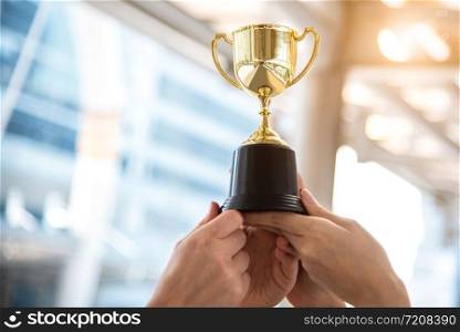Champion golden trophy for winner with sport player hands in sport stadium background. Success and achievement concept. Sport and cup award theme. American football award and match game play prize