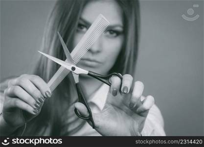 Change of look, new image. Young girl presents comb and scissors. Female stylist preparing equipment to work cut long straight healthy hair.. Prepared girl to cut her long straight hair.