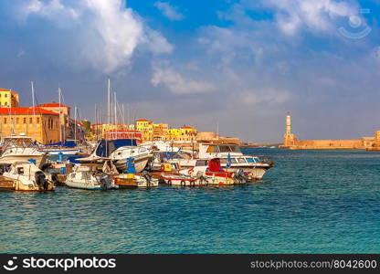 Chania Arsenals, the Venetian shipyards, and fishing boats in old harbour of Chania with Lighthouse in sunny and cloudy summer morning, Crete, Greece