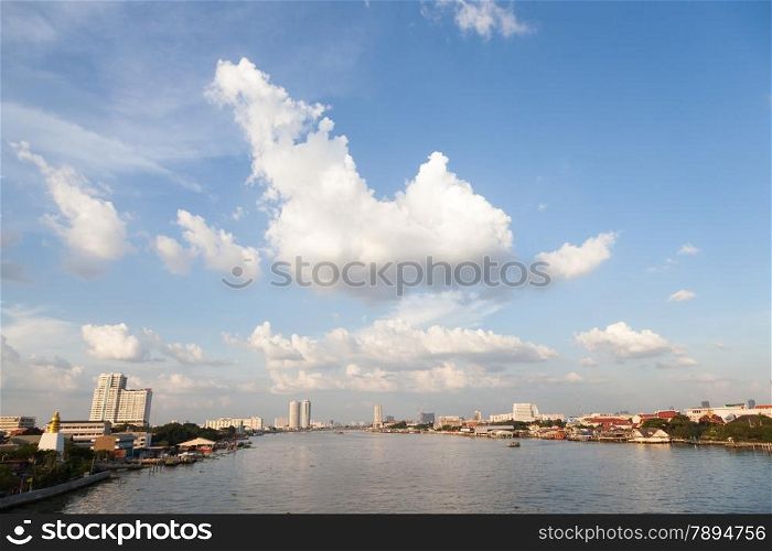 Chao Phraya River. With buildings and skyscrapers near river. During the day, the sky is clear.
