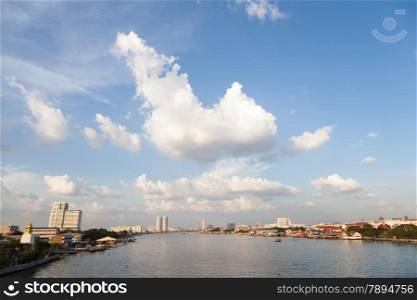 Chao Phraya River. With buildings and skyscrapers near river. During the day, the sky is clear.