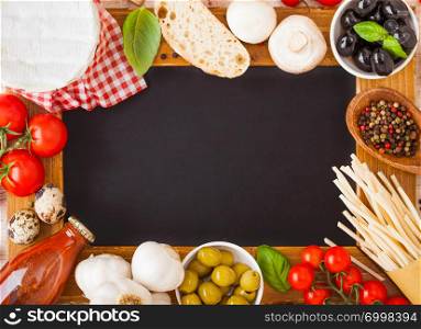 Charcoal wooden menu board with homemade spaghetti pasta with quail eggs and cheese on wood background. Classic italian village food. Garlic, champignons, black and green olives, wooden spatula.