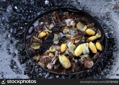 Charcoals and dish with potates in oven