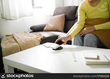 Charging mobile phone battery with wireless charging device in the table. Smartphone charging on a charging pad. Mobile phone near wireless charger.