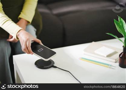 Charging mobile phone battery with wireless charging device in the table. Smartphone charging on a charging pad. Mobile phone near wireless charger.