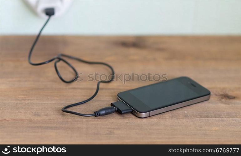 charging mobile phone on wooden table