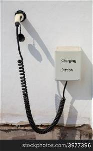 Charging point for electric car on white wall of house