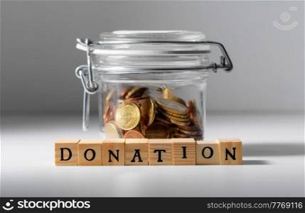 charity and financial help concept - close up of coins in glass jar for donation. coins in glass jar for donation