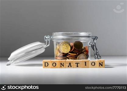 charity and financial help concept - close up of coins in glass jar for donation. coins in glass jar for donation