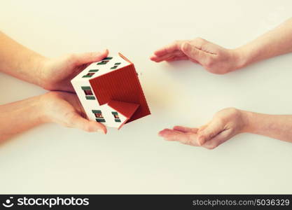 charity, building, sale, real estate and property concept - close up of hands giving and receiving house or home model. close up of hands giving house or home model