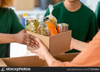 charity, donation and volunteering concept - close up of volunteers giving box of food at distribution or refugee assistance center. volunteers give food at refugee assistance center