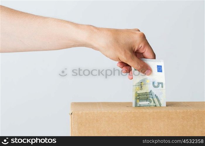 charity, finances, funding, investment and people concept - male hand putting euro money into donation box