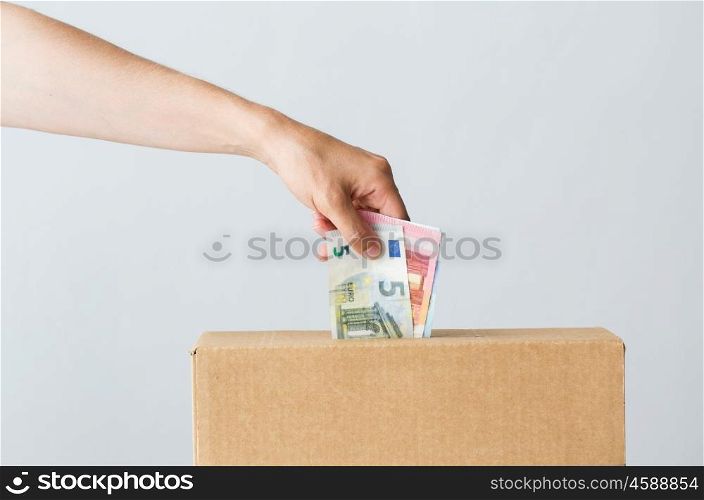charity, finances, funding, investment and people concept - man putting euro money into donation box