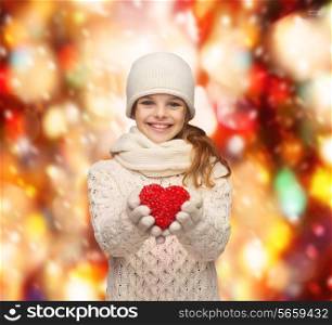 charity, happiness and love concept - smiling teenage girl in winter clothes with small red heart