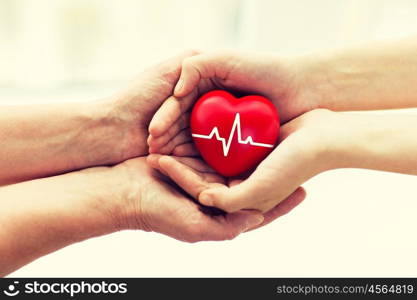 charity, health care, donation and medicine concept - man hand giving red heart with cardiogram to woman