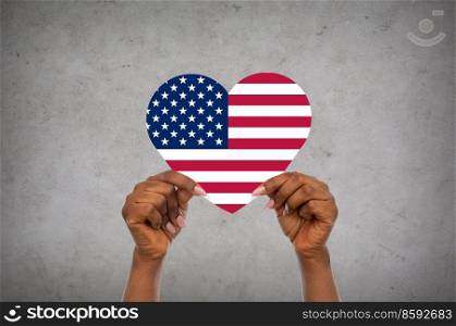 charity, love and national concept - close up of hands holding heart in colors of flag of united states of america over grey stone background. hands holding heart in colors of flag of america