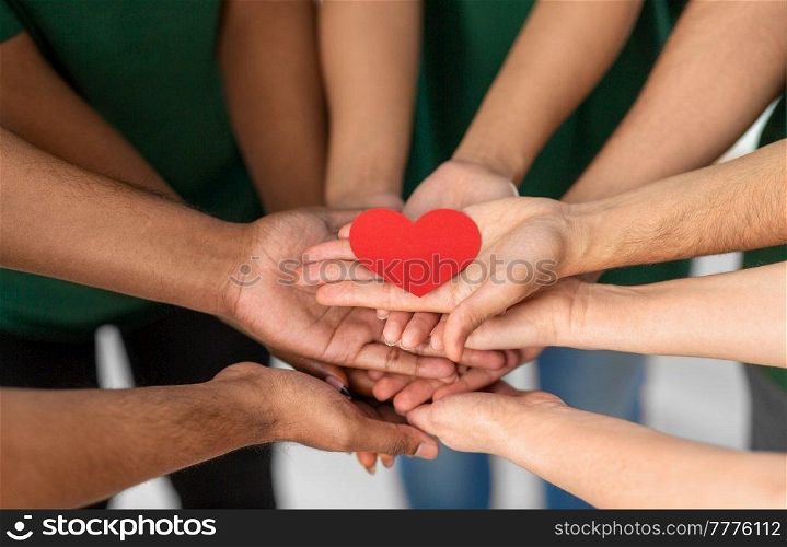 charity, support and volunteering concept - close up of volunteers&rsquo;s hands holding red heart at distribution or refugee assistance center. close up of volunteers&rsquo;s hands holding red heart