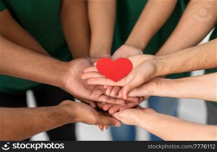charity, support and volunteering concept - close up of volunteers&rsquo;s hands holding red heart at distribution or refugee assistance center. close up of volunteers&rsquo;s hands holding red heart