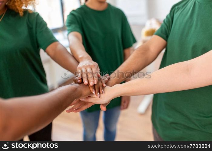 charity, support and volunteering concept - close up of volunteers stacking hands at distribution or refugee assistance center. close up of volunteers stacking hands