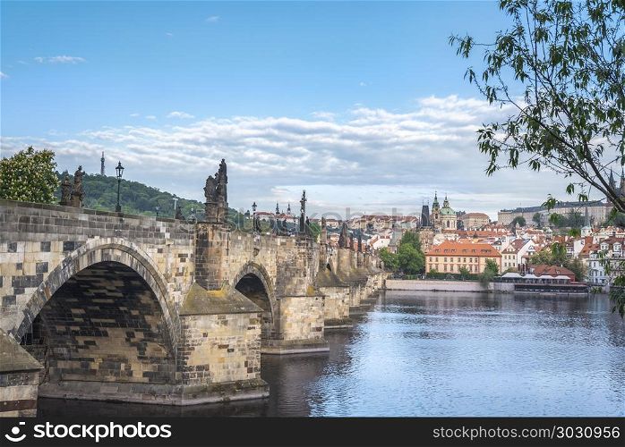 Charles Bridge on the side and Prague city. Charles Bridge, a Czech architecture in gothic-style with baroque statues, crossing the Vltava river and the Prague city, in Czech Republic.