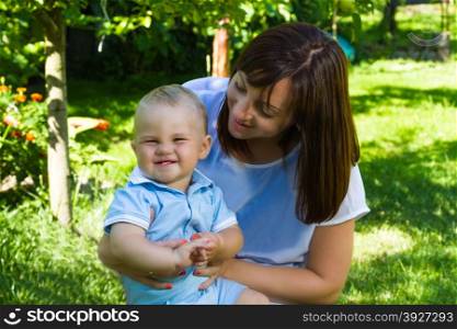 charming caucasian baby boy with mother in garden