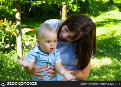 charming caucasian baby boy with mother in garden