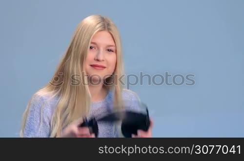 Charming girl with headphones listening to music on a white background. Smiling young woman slowly puts headphones over her ears, reacts to the music and sways along the beat.