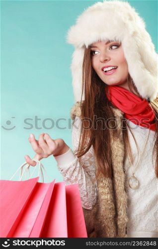 Charming gorgeous woman with bags shopping. Young girl in fur hat in studio blue. Winter fashion clothes sale.. Woman with bags shopping. Winter fashion.