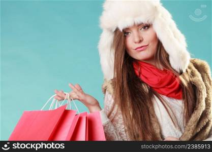 Charming gorgeous woman with bags shopping. Young girl in fur hat in studio blue. Winter fashion clothes sale.. Woman with bags shopping. Winter fashion.