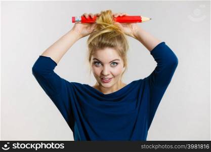 Charming happy blonde woman having big pencil in hair having fun, education ideas.. Happy blonde woman having big pencil in hair