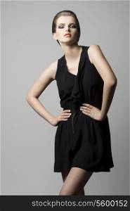 charming lady with brown elegant hair-style, pretty make-up and black dress in fashion pose