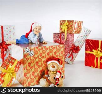 Charming little boy among the Christmas gifts