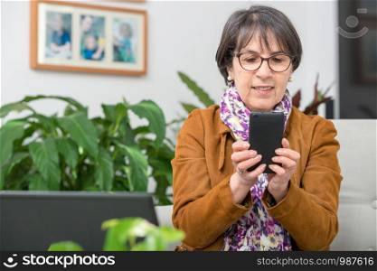 charming mature woman with brown jacket talking on phone at home
