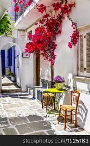 Charming narrow typical streets of Greek islands. Ios, Chora town with pink floral tree. Cyclades, Greece