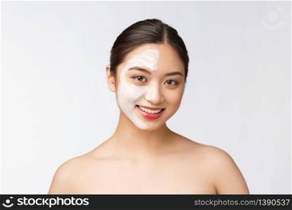 Charming pleasant woman applying cream on half face.. Charming pleasant woman applying cream on half face