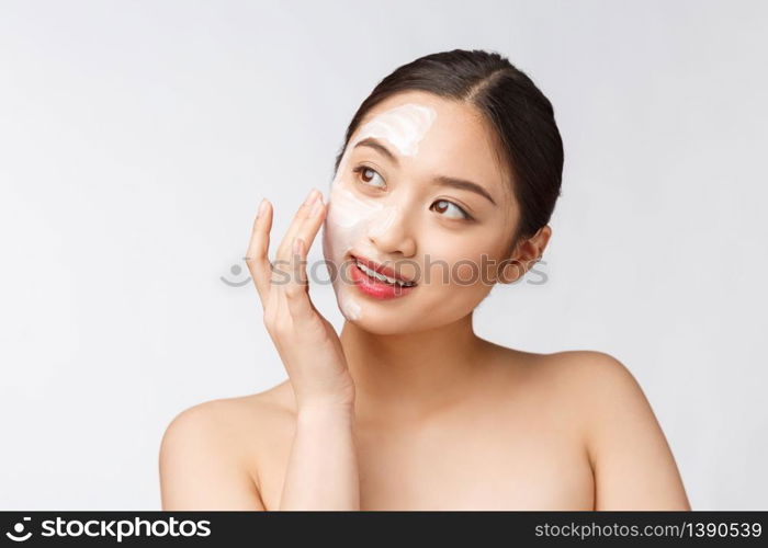 Charming pleasant woman applying cream on half face.. Charming pleasant woman applying cream on half face