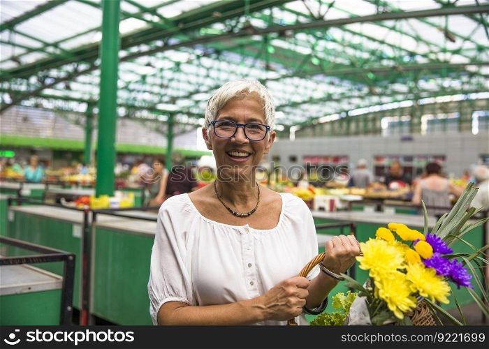 Charming senior woman buying fresh flowers on market