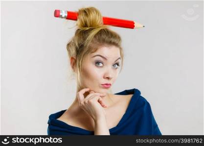 Charming thinking blonde woman having big pencil in hair having something on her mind, education ideas.. Thinking blonde woman having big pencil in hair