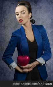 charming woman in fashion portrait wearing elegant blue jacket and creative heart shaped bag in the hands
