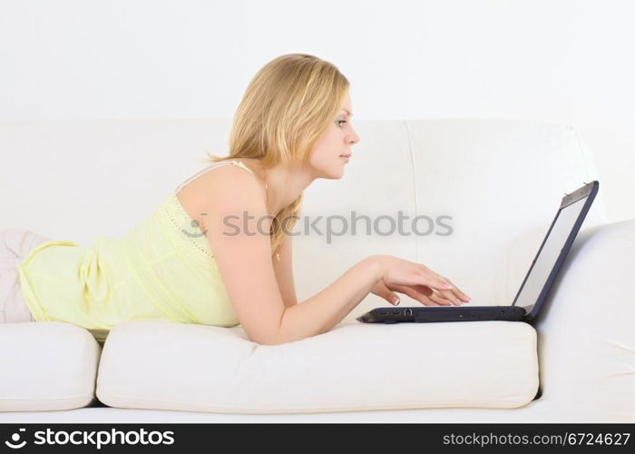 charming woman lying on a sofa with laptop