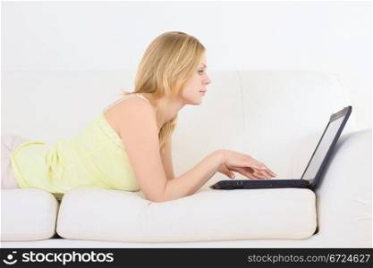 charming woman lying on a sofa with laptop