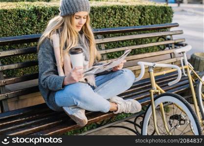 charming woman reading newspaper bench