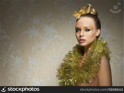 charming woman with freckles posing with glossy golden creative christmas make-up, tinsel around neck and lovely ribbon on hair-style