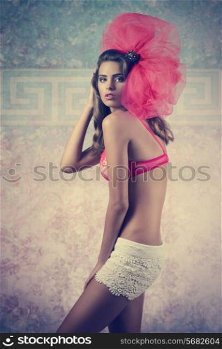 charming young girl with perfect body wearing red bra and white shorts, posing with big tulle creative accessory on the head, fashion pose