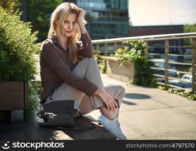 Charming young lady resting on the wooden bench