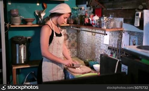 Charming young woman chopping garlic on cutting board to make a delicious meal . Process of cutting garlic in the kitchen