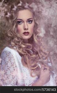 charming young woman posing in vintage fashion portrait with long blonde curly hair, white elegant dress and stylish make-up.