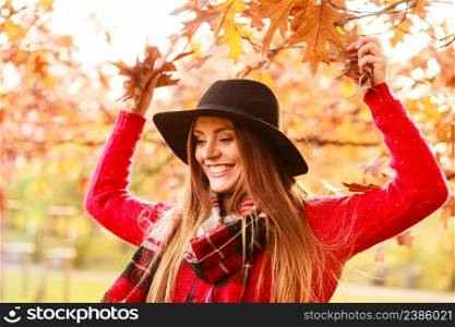 Charming young woman walking in autumnal park. Fashionable girl wearing red sweater plaid scarf and black hat.. Charming woman walking in autumnal park