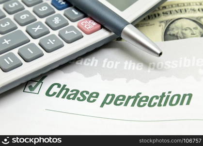 Chase perfection printed on book with calculator and pen.